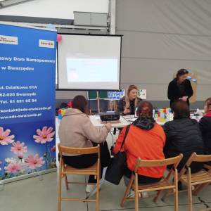 Stoisko Środowiskowego Domu Samopomocy w Swarzędzu. Przy stolikach trwają zapisy i konsultacje; obok roll-up z danymi kontaktowymi ośrodka.