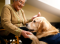 Starsza kobieta na wózku inwalidzkim głaszcze psa rasy golden retriever, który podaje jej łapę, symbolizując wsparcie i więź między nimi.