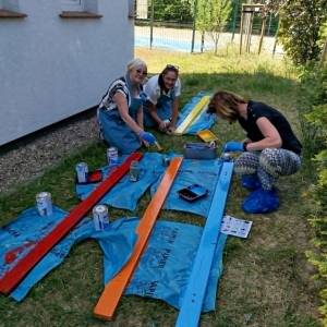 Członkowie stowarzyszenia i uczestnicy ŚDS malują kolorowe elementy przeznaczone do odnowienia Ławki Dobrych Słów